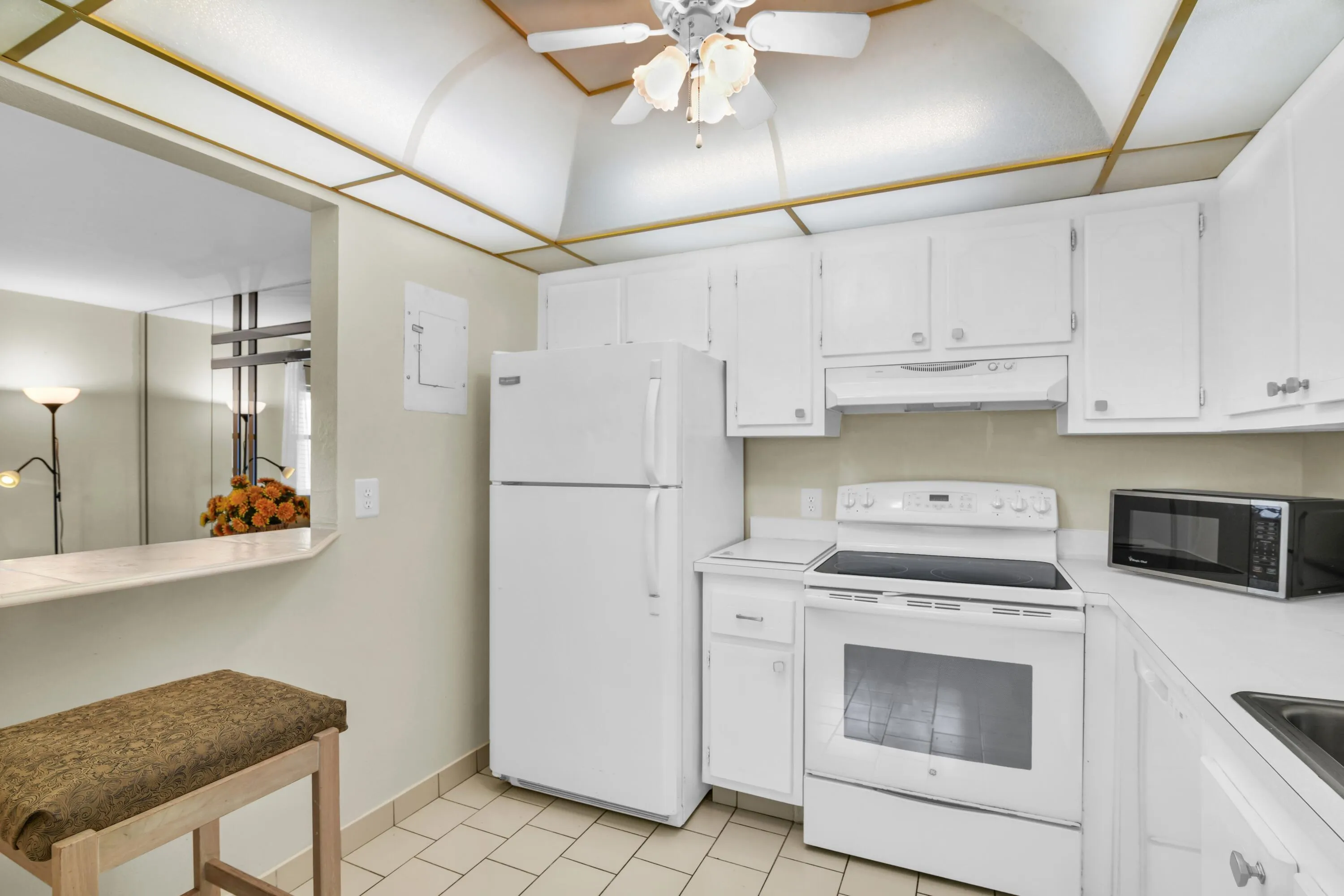 Kitchen featuring white cabinetry, white appliances, tile flooring, a breakfast bar, and a drop ceiling with integrated lighting