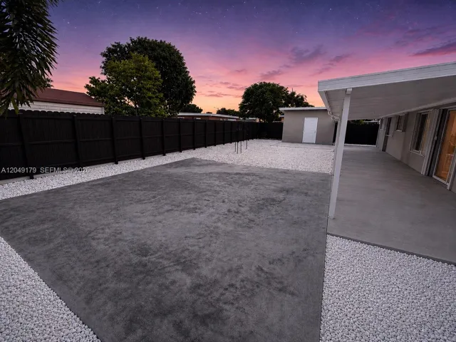 Designed for year-round outdoor enjoyment, the backyard features an insulated covered patio with rain gutters, an expansive concrete patio, a detached utility/storage building, and a new bronze Dura Fence enclosing the property.