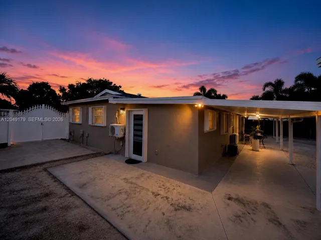 Side elevation showcasing the expansive insulated covered patio with integrated rain gutters, extensive concrete walkways, and hurricane shutters for added protection and peace of mind.