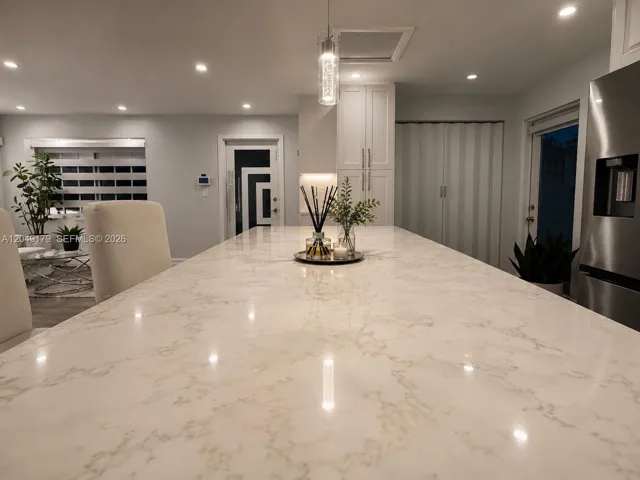 The oversized quartz island serves as the heart of the home—perfect for gathering, entertaining, casual dining, and everyday living.