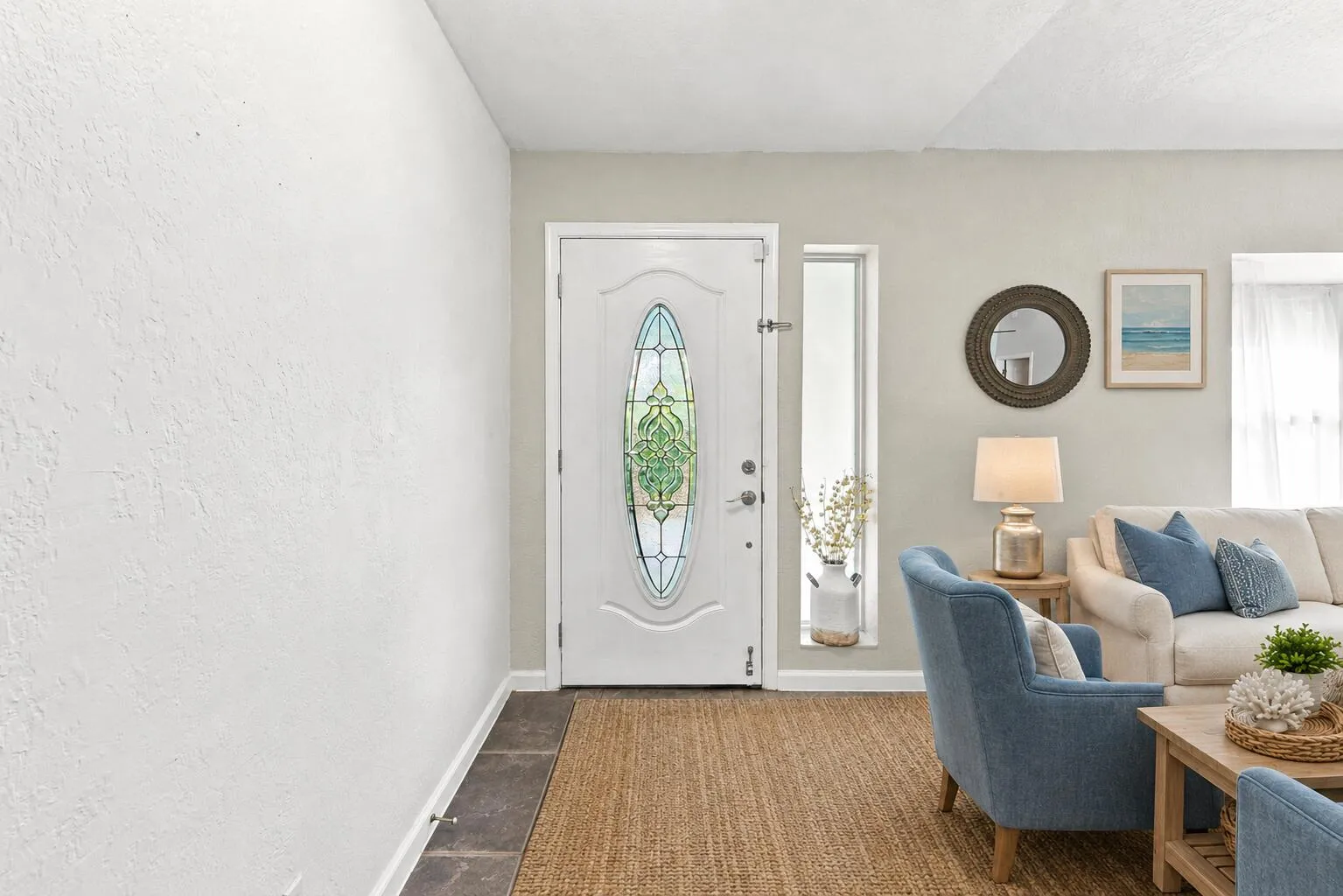 Entryway featuring an ornate glass-paneled door, natural fiber rug, and stone tile flooring