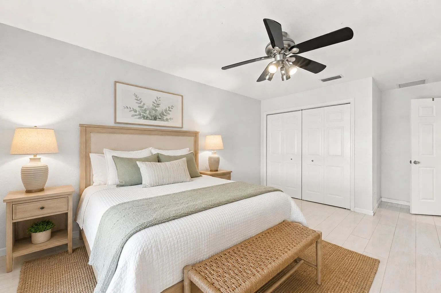 Spacious room featuring light wood-finish flooring, a ceiling fan with integrated lighting, and white bi-fold closet doors