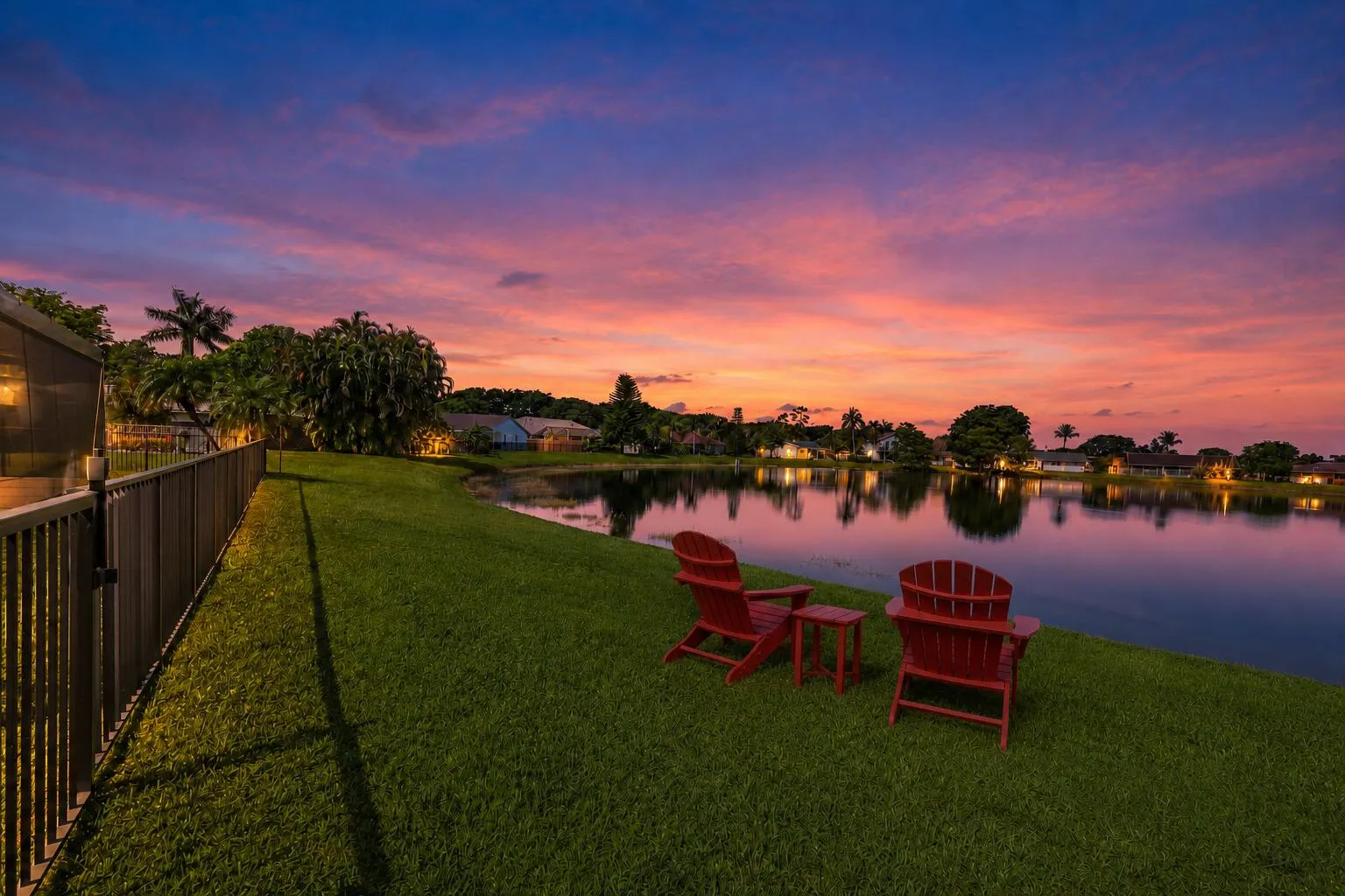 Expansive waterfront yard with a manicured lawn and a black metal fence
