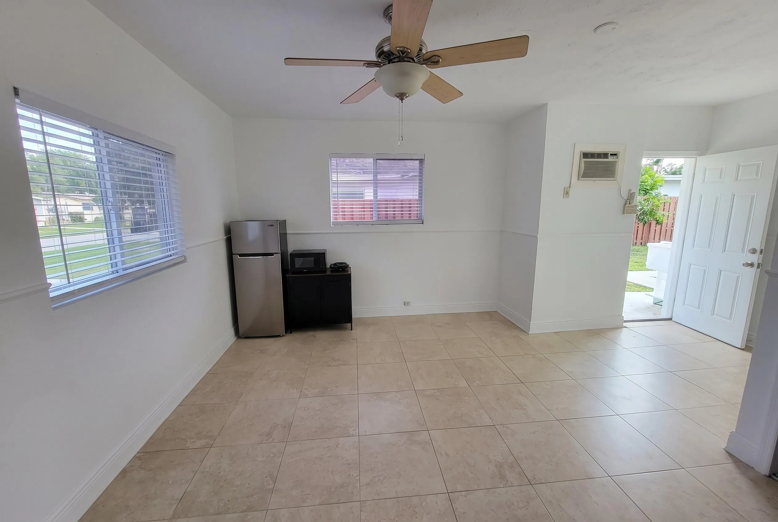 Spacious room with neutral tile flooring and white walls