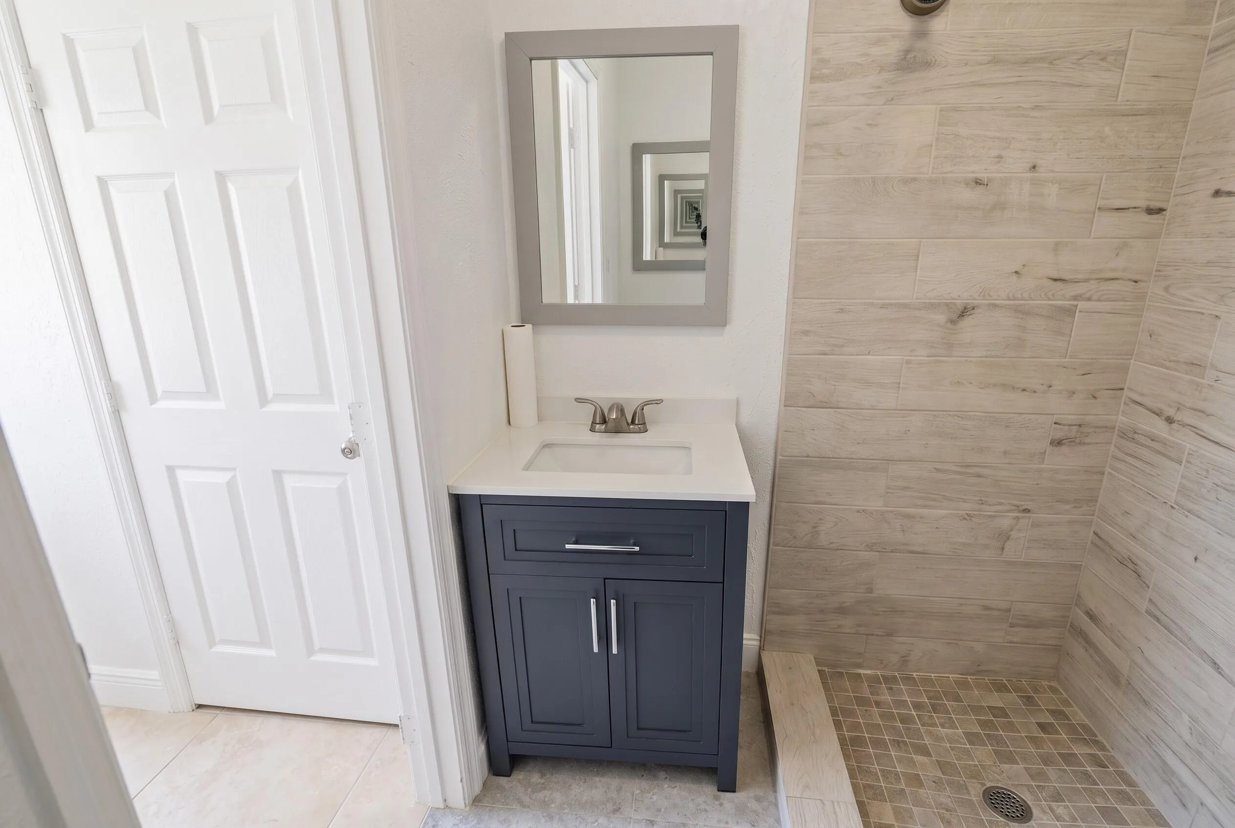 Bathroom vanity with white countertop and integrated sink, framed mirror, and chrome faucet