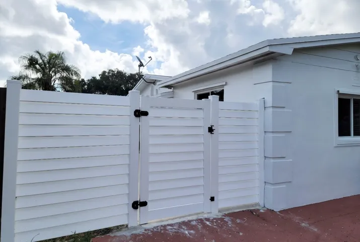 White horizontal slat fencing with a gate, featuring black hardware