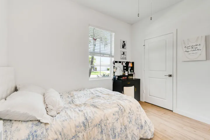 Bright interior room featuring wood-plank tile flooring, a white paneled door with brushed nickel hardware, and a window with horizontal blinds