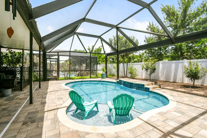 Picture Window custom pool enclosure with a freeform heated saltwater pool, paver patio and covered lanai for living and dining outdoors.