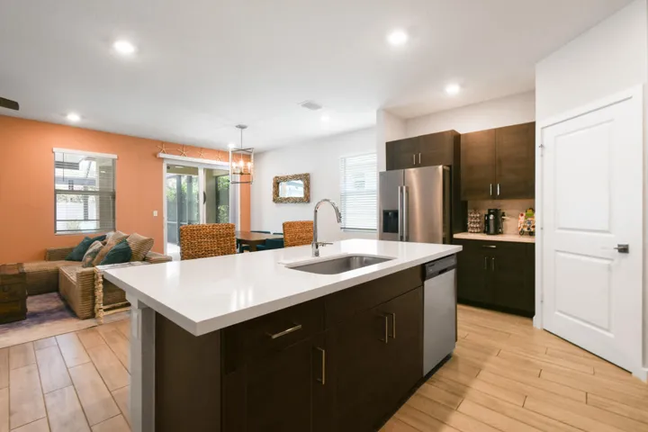 Modern kitchen featuring a large island with white countertop, integrated sink, and stainless steel dishwasher