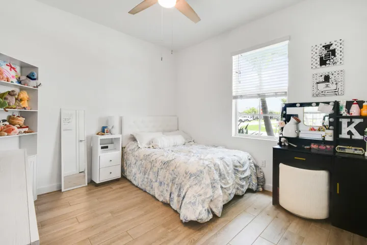 Bright interior space featuring wood-finish flooring, a ceiling fan, and a large window with blinds