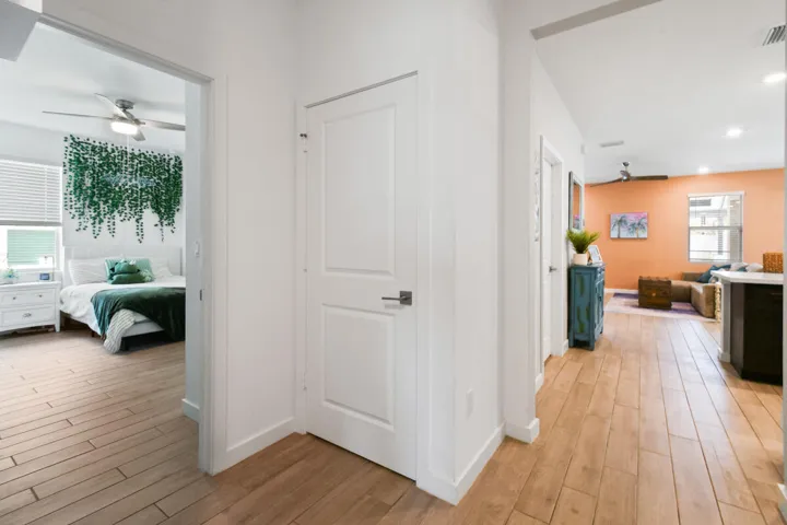 Hallway featuring wood-plank tile flooring extending into living areas and a brightly lit bedroom with white paneled doors.