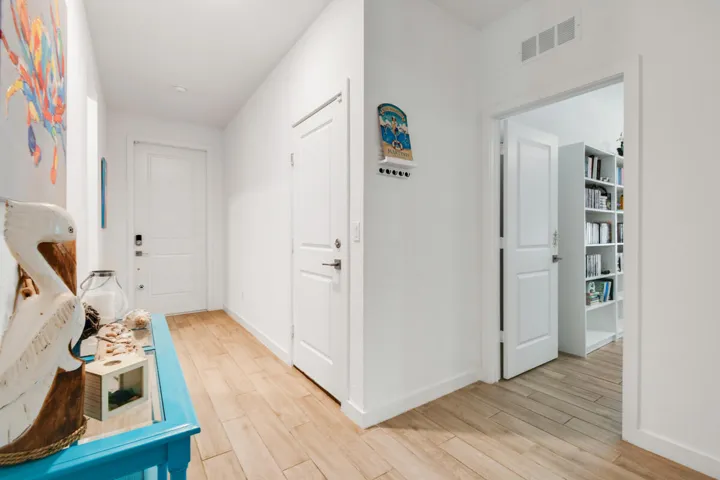 Bright hallway with light wood-plank flooring, white walls, and white trim