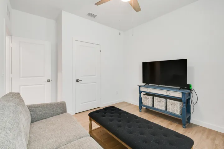 Bonus 4th BR or Den featuring light-toned wood plank tile flooring, bright white walls, two panel doors, and a ceiling fan with integrated lighting