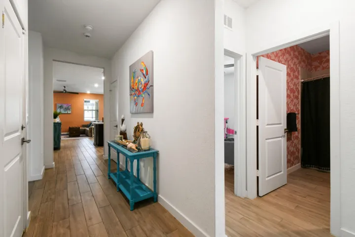 Hallway to 2 bedrooms in triple split floorplan featuring wood-plank tile flooring, white trim, and recessed lighting.