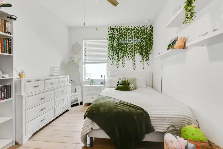 Bedroom featuring light wood-finish flooring, white walls, and a window with blinds