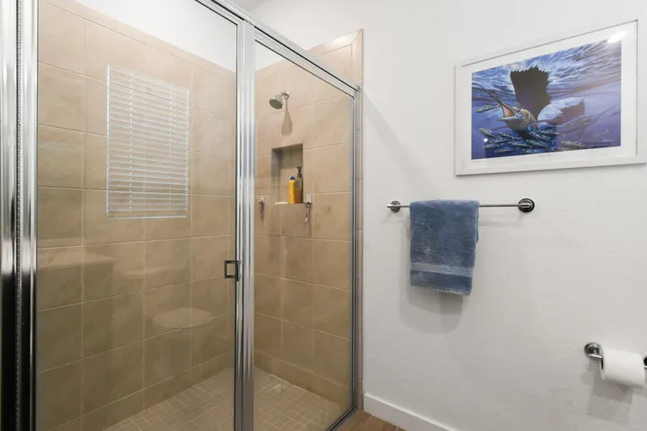 Glass shower enclosure featuring sand-toned tile walls and a built-in niche