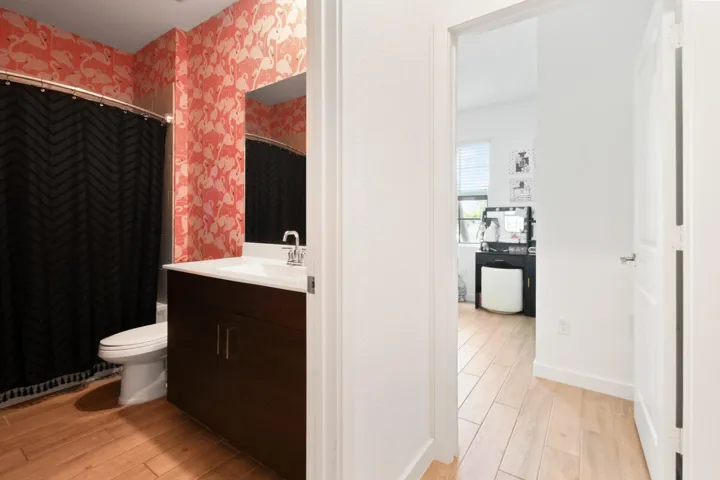 Bathroom featuring a vanity with a white countertop and dark wood-finish cabinetry, a toilet, and patterned wall covering