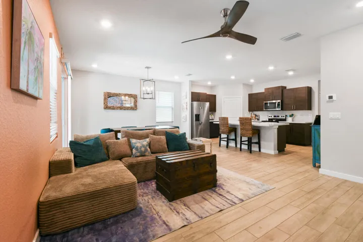 Open-concept living area featuring light wood-plank tile flooring, recessed lighting, and a modern ceiling fan