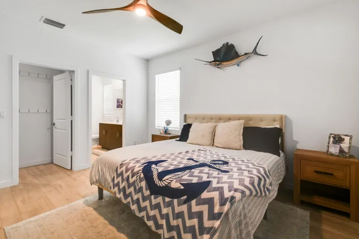 Bedroom featuring light wood-plank tile flooring and a contemporary ceiling fan with ensuite bath