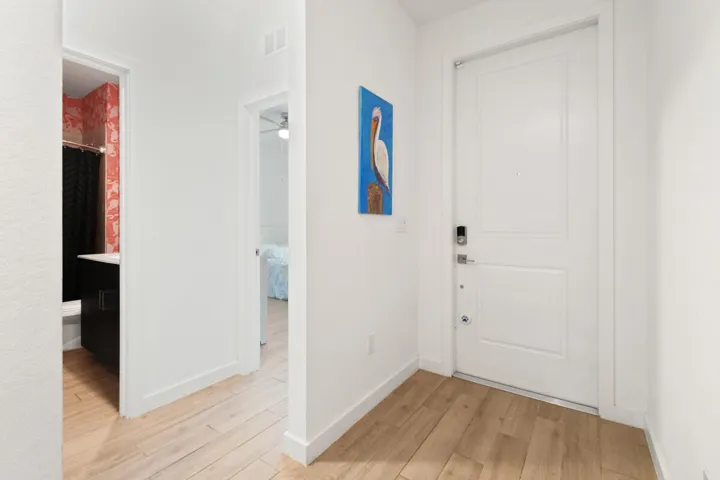 Entryway featuring wood-plank tile flooring, a contemporary white panel door with smart lock hardware, and bright white wall finishes