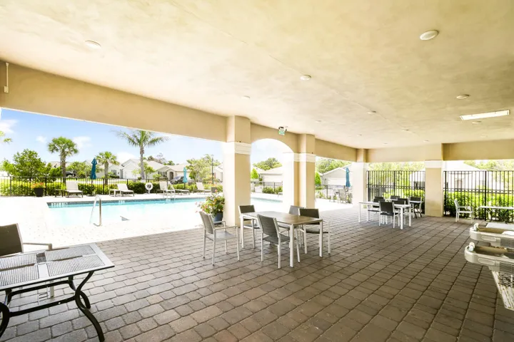 Covered patio featuring paver flooring, multiple seating areas, and direct access to the outdoor swimming pool