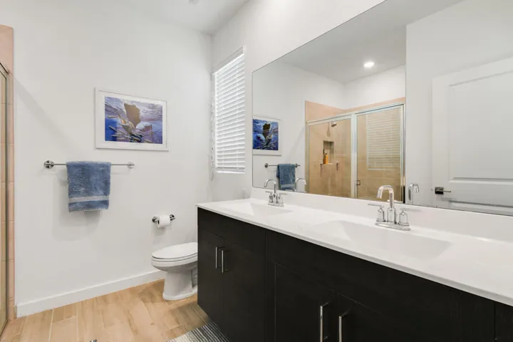 Dual vanity with white undermount sinks and chrome fixtures with spacious tiled shower