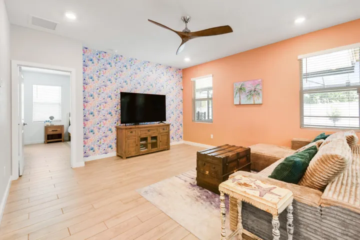 Spacious living area featuring light wood-plank tile flooring, a contemporary ceiling fan, and recessed lighting