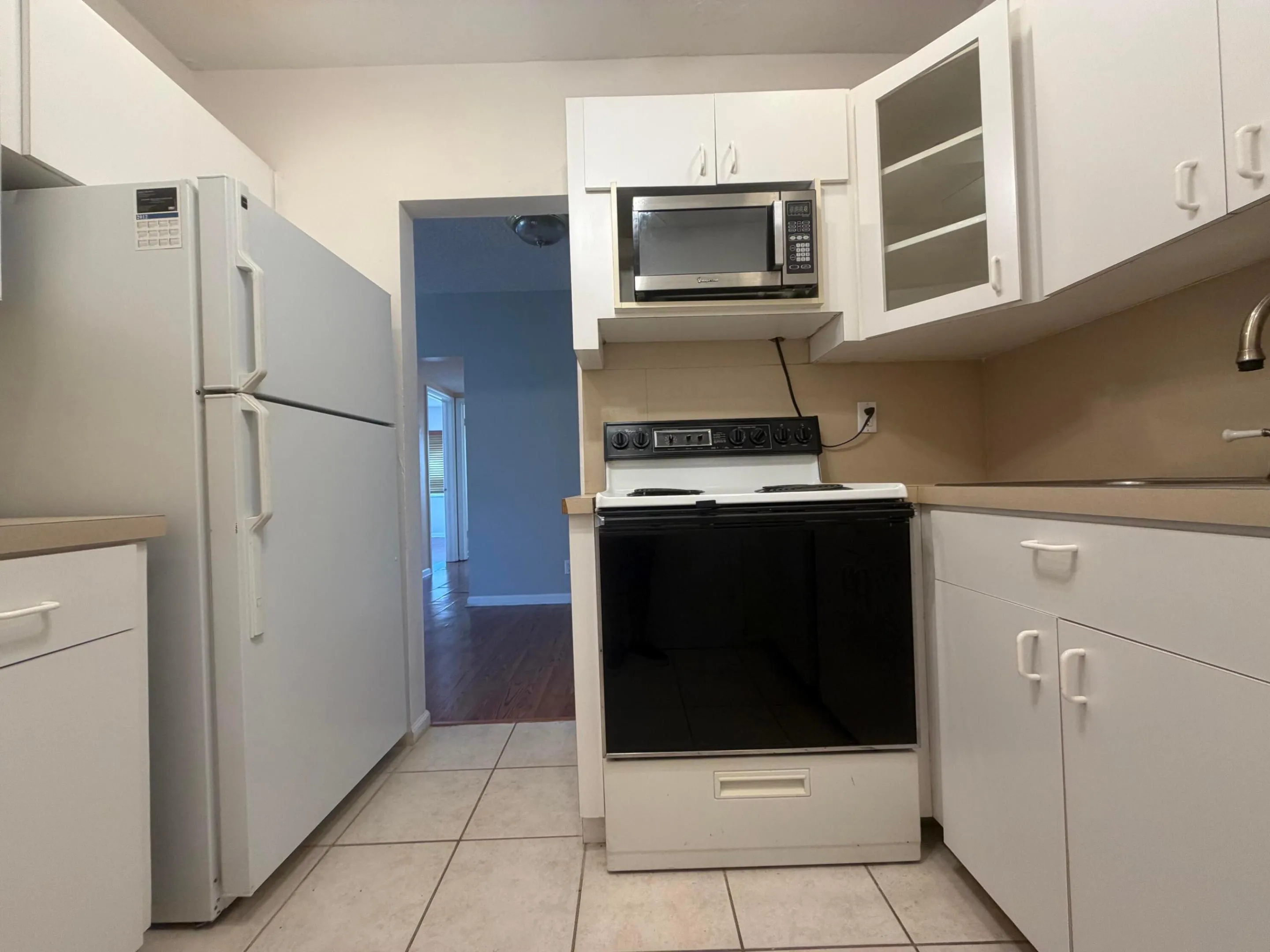 Kichen offers white tile foors with laminate contertops and elecric stove.