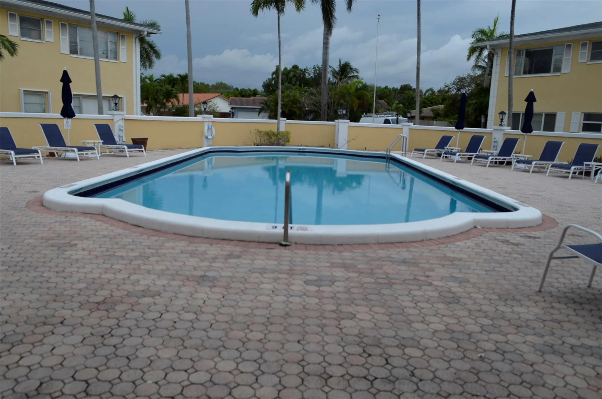 Swimming pool with a paver deck surround, featuring a white coping and a blue-tiled waterline