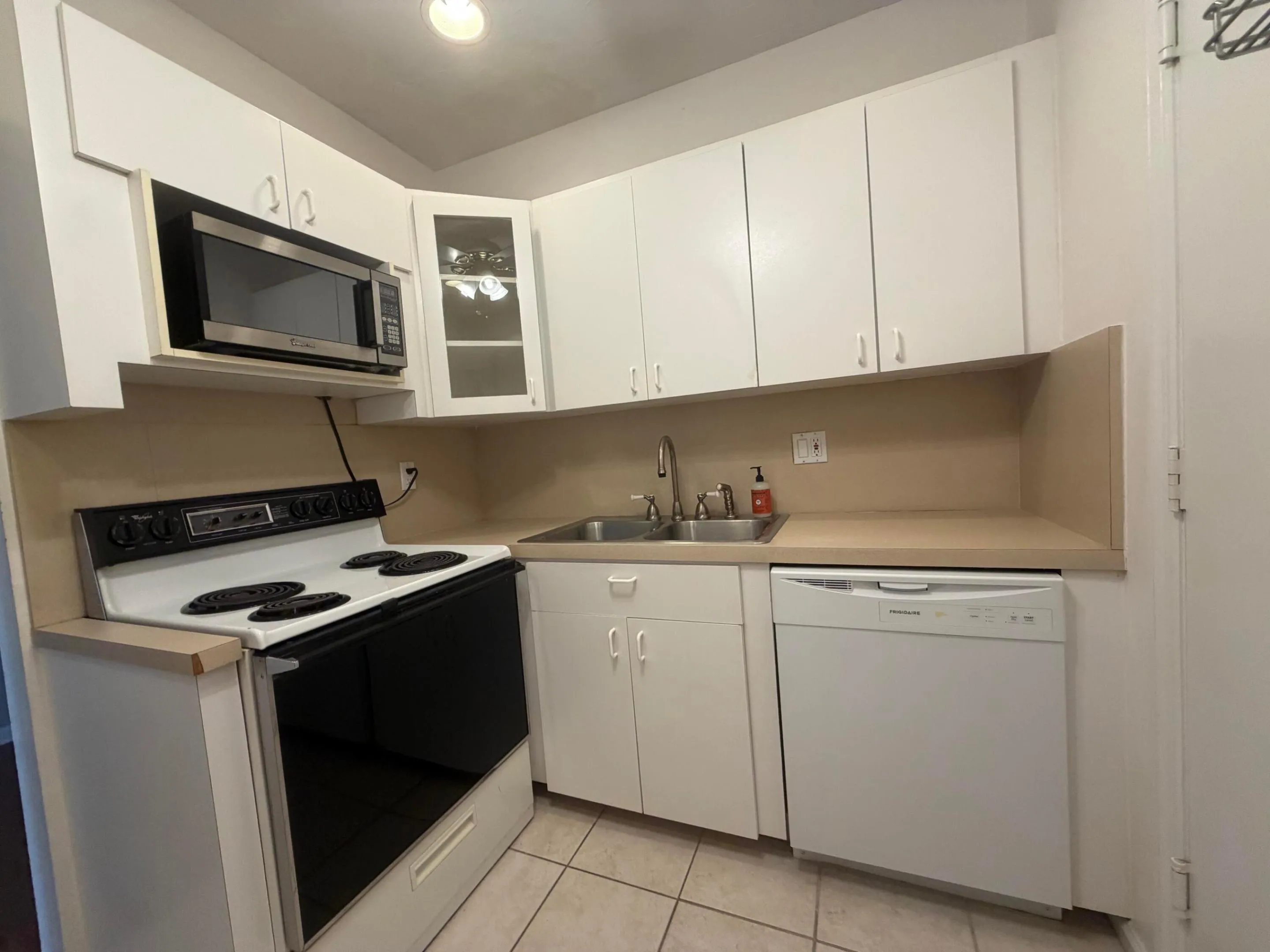 Compact kitchen featuring white cabinetry, a built-in electric range, and dishwasher.