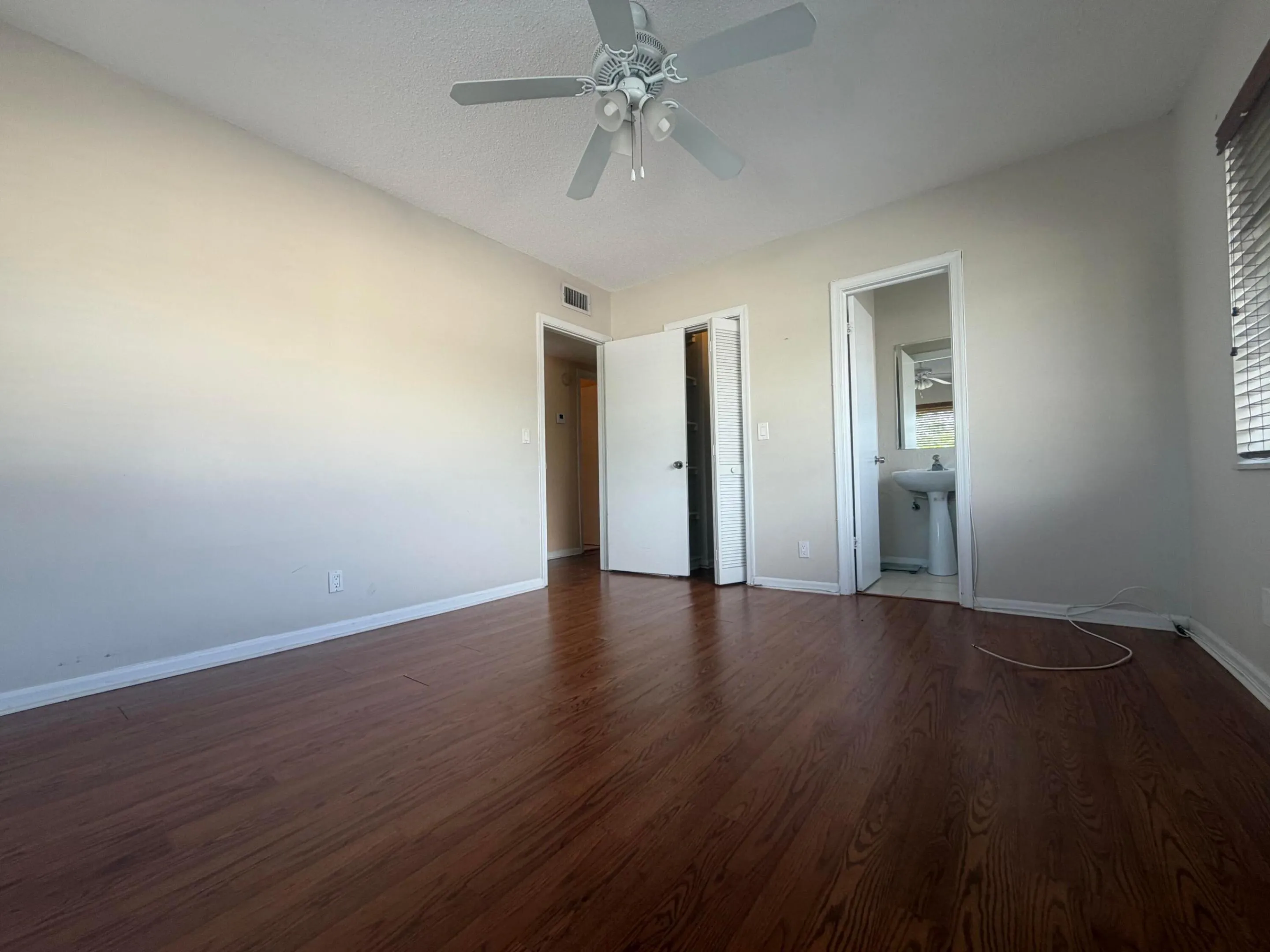 Bedroom featuring wood-finish flooring and light-toned walls, 1/2 bathroom, and walk-in closet