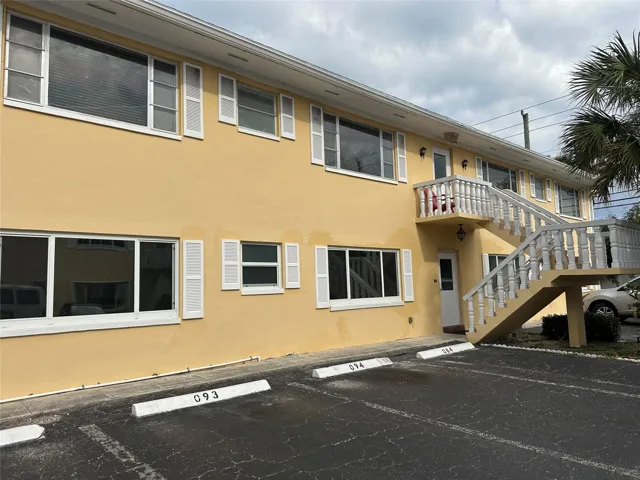 Two-story building featuring a stucco exterior and white louvered shutters