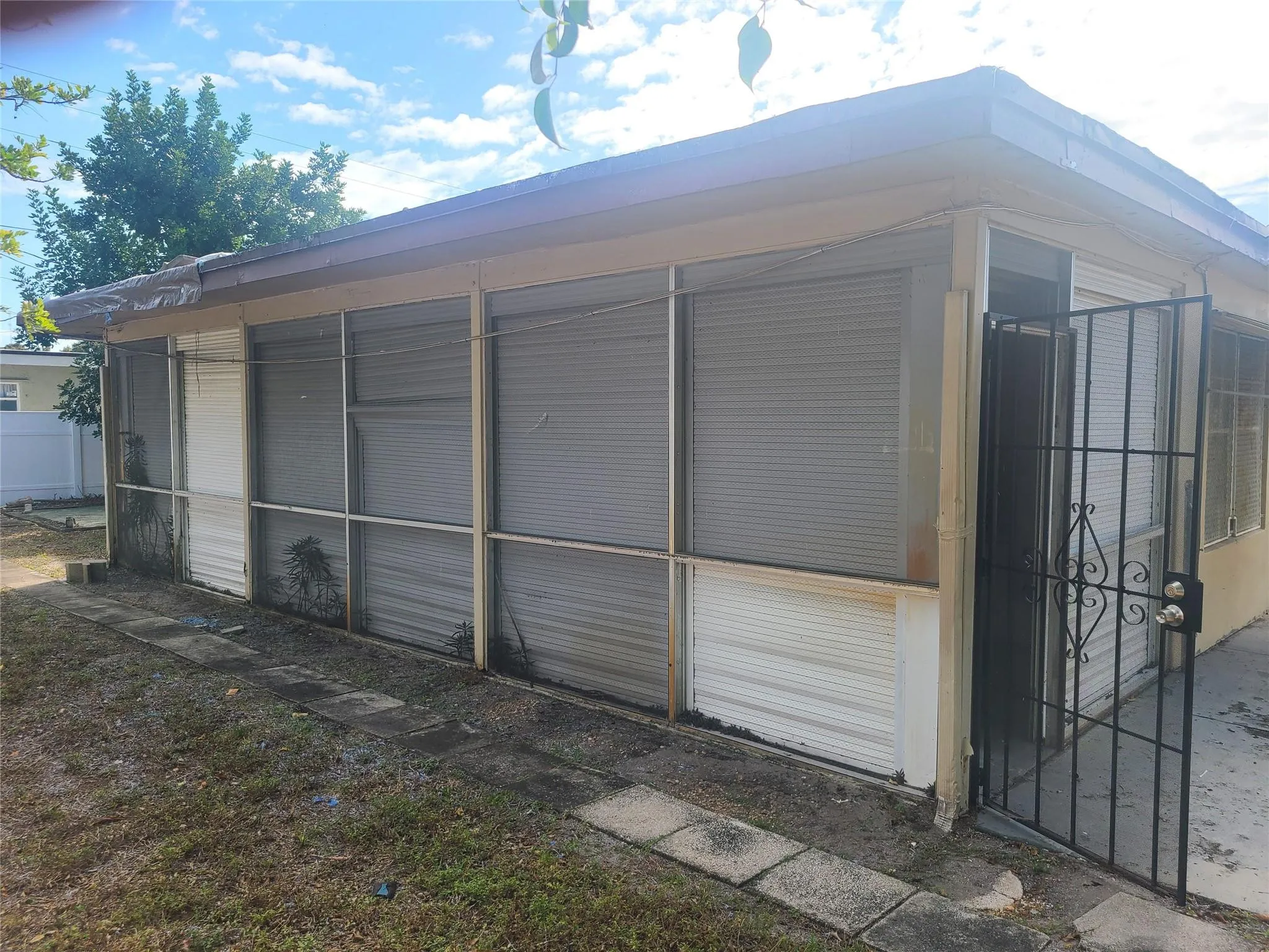 Screened enclosure with an ornate security gate and concrete tile path