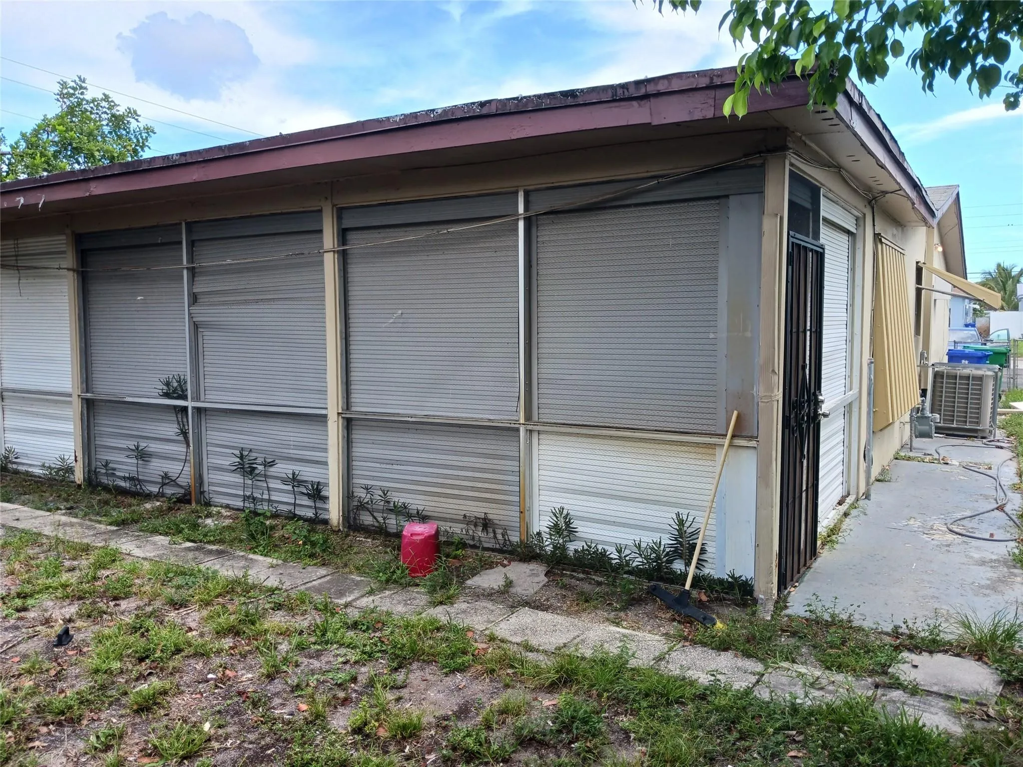 Exterior featuring multiple roll-down hurricane shutters, a covered walkway, and a side entrance with a security door