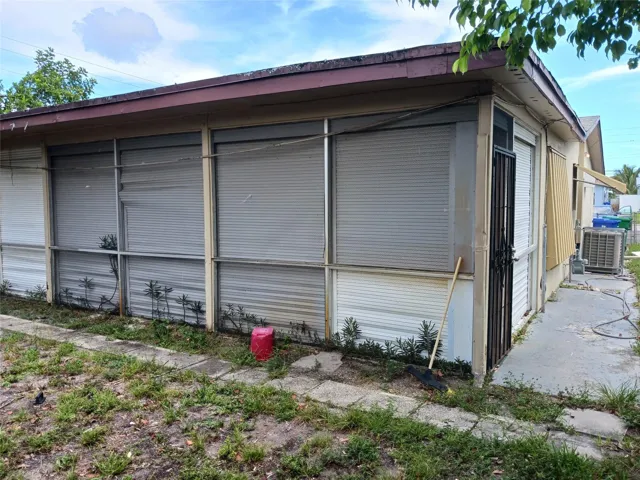 Exterior featuring multiple roll-down hurricane shutters, a covered walkway, and a side entrance with a security door
