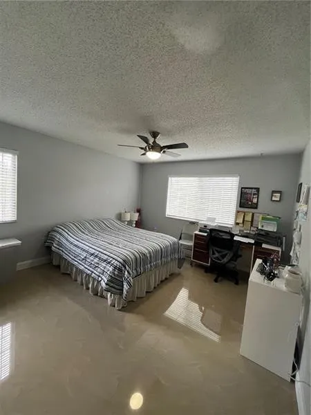 Spacious room featuring polished tile flooring and multiple windows with horizontal blinds