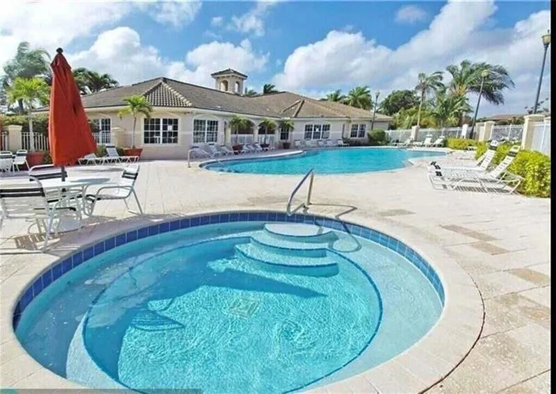 Outdoor aquatic area featuring a circular spa with integrated steps, a large swimming pool, and a surrounding paver deck