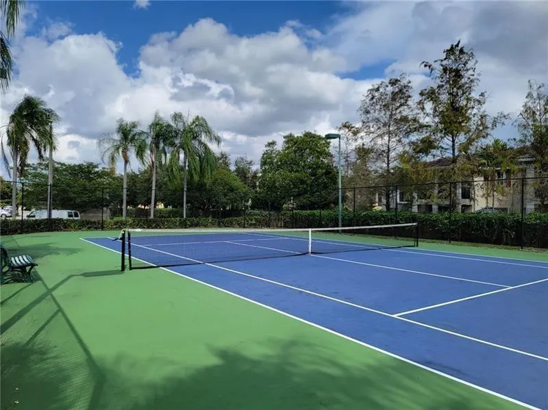 Regulation-size tennis court featuring a blue playing surface and green surrounds