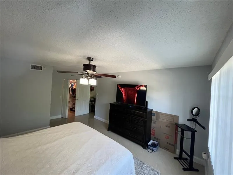 Room featuring light gray walls and a wood-finish ceiling fan with integrated lighting
