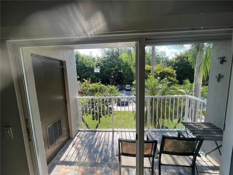 Sliding glass door access to an outdoor patio featuring stone-finish flooring and a white railing