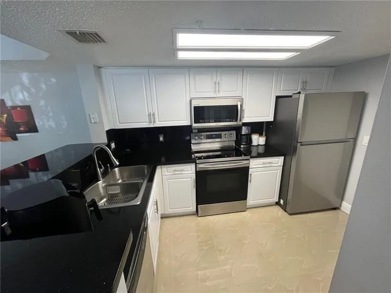 Modern kitchen featuring white cabinetry, dark countertops, and a stainless steel appliance suite