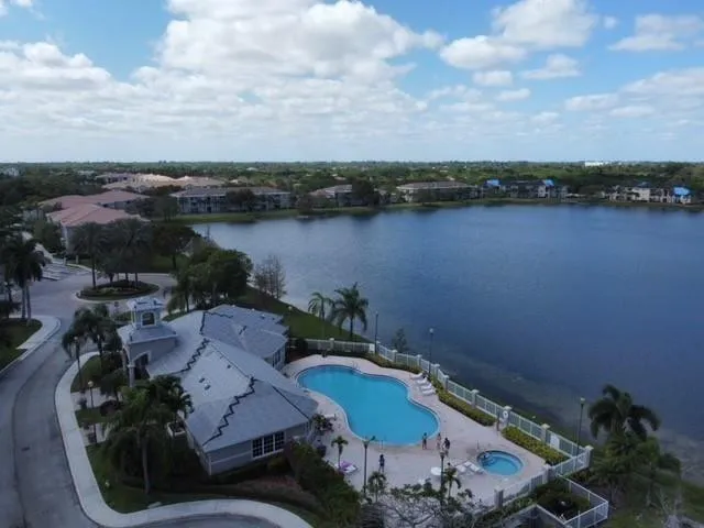 Community amenities featuring a lakefront pool, adjacent hot tub, and a clubhouse with a central cupola