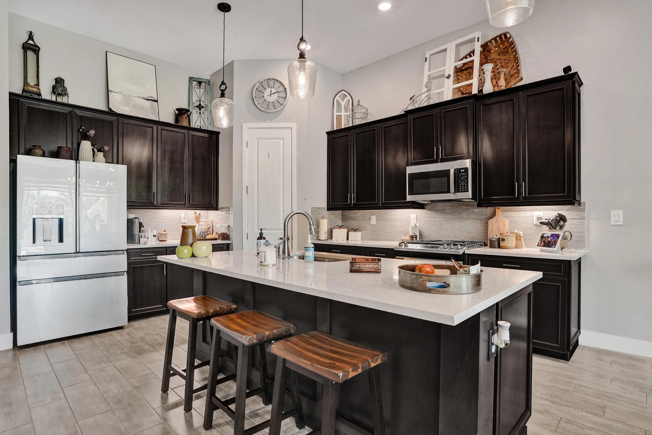 Kitchen featuring dark wood cabinetry with under-cabinet lighting, a center island with quartz countertop, stainless steel appliances