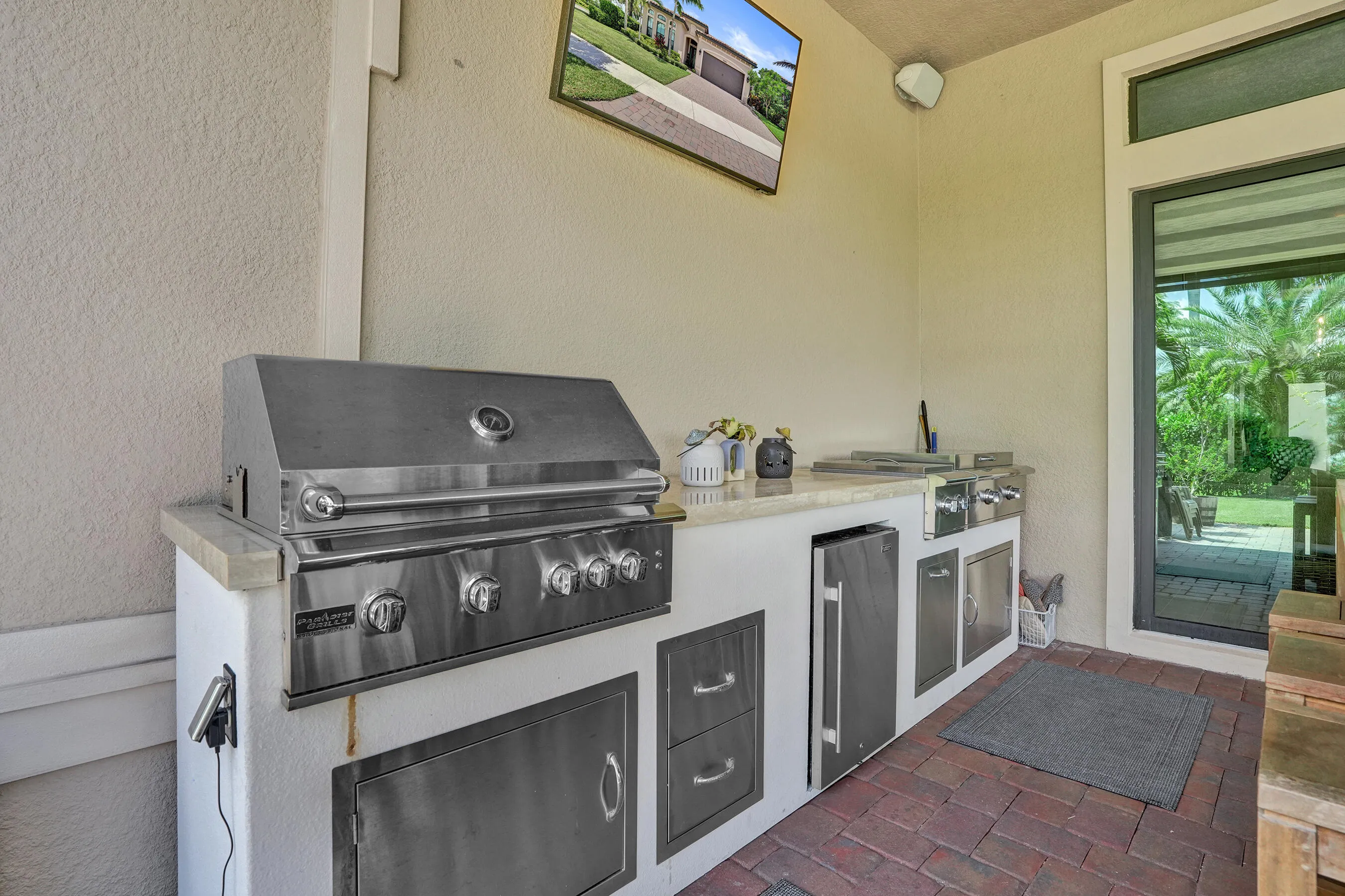Outdoor kitchen featuring a built-in stainless steel grill, integrated mini-refrigerator