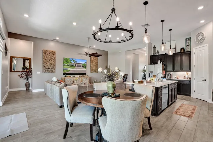 Open-concept living space featuring ceramic tile flooring throughout, recessed lighting, pendant lights over the center island and contemporary chandelier over the dining table