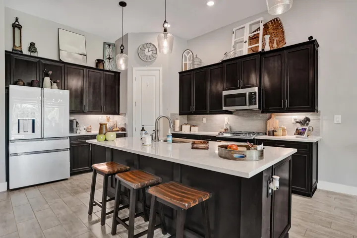 Kitchen featuring dark wood cabinetry with under-cabinet lighting, a center island with quartz countertop, stainless steel appliances