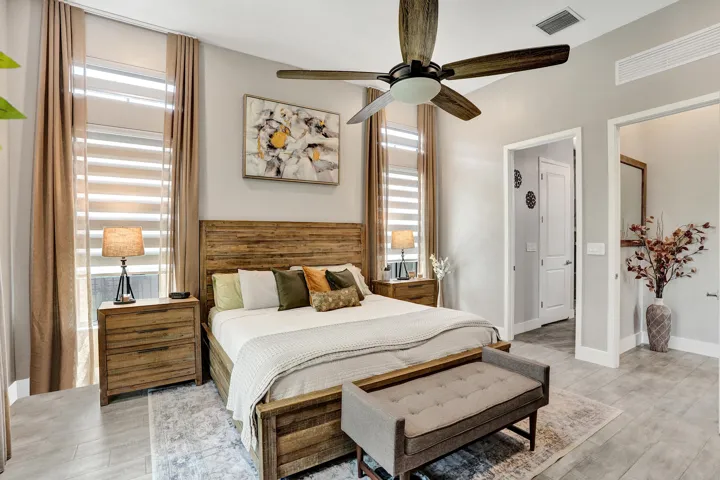 Spacious room featuring ceramic tile flooring, ceiling fan, large windows with zebra blinds and drapes