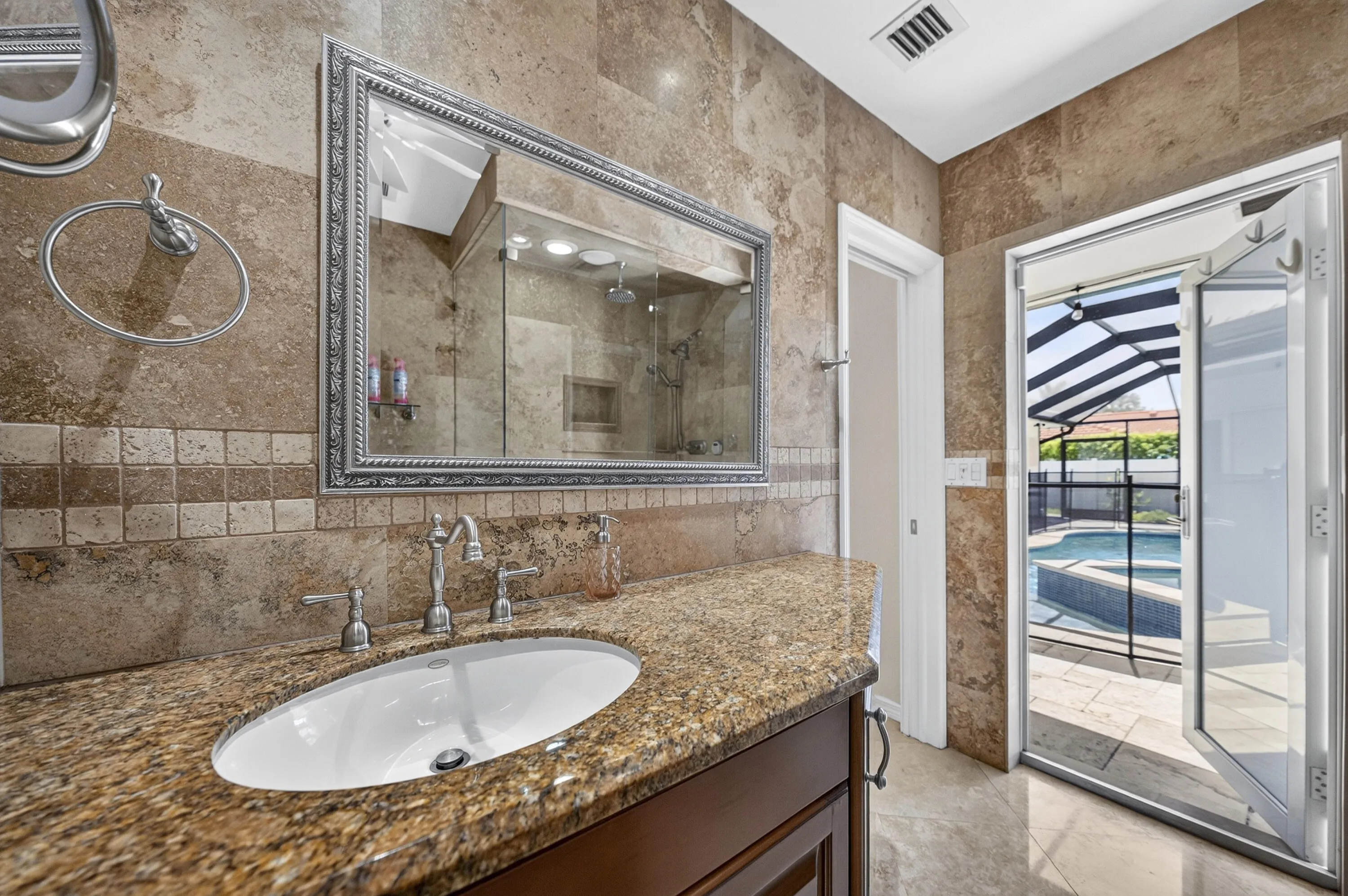 Bathroom vanity featuring a polished stone countertop, undermount sink, and ornate framed mirror