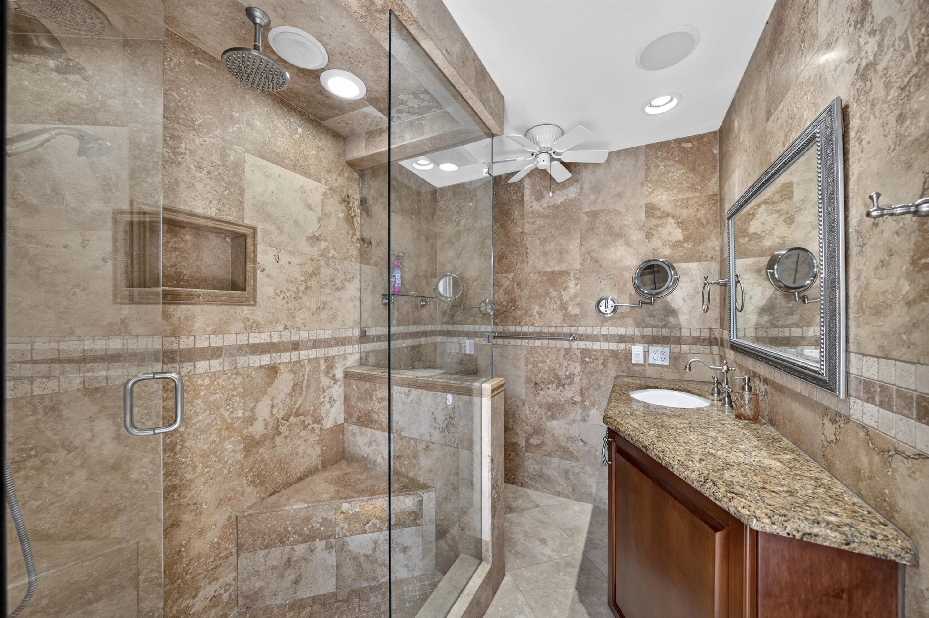 Tiled bathroom featuring a glass-enclosed steam shower with a built-in bench and recessed shelf