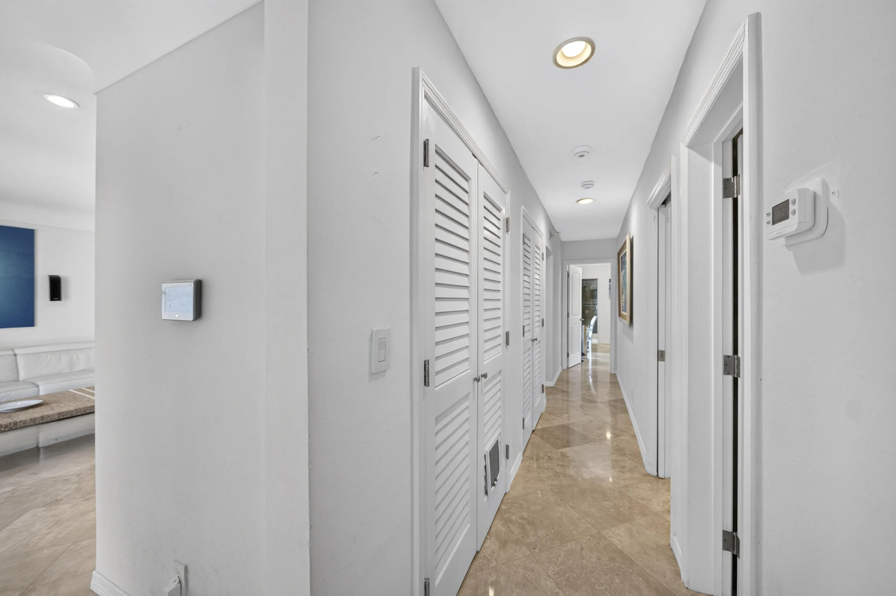 Hallway featuring recessed lighting, louvered bi-fold doors, multiple doorways, and marble flooring